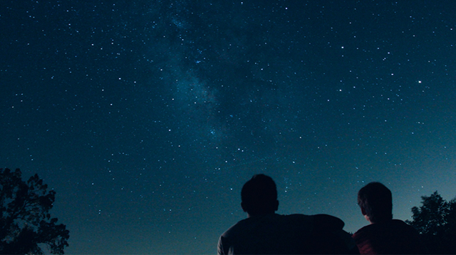 Silhouette of two people looking up at a starry night sky